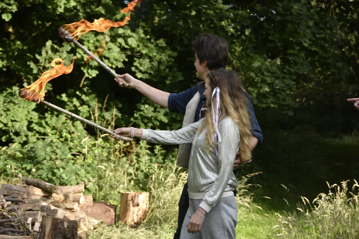 Lighting a torch from the fire at the edge of the woodland
